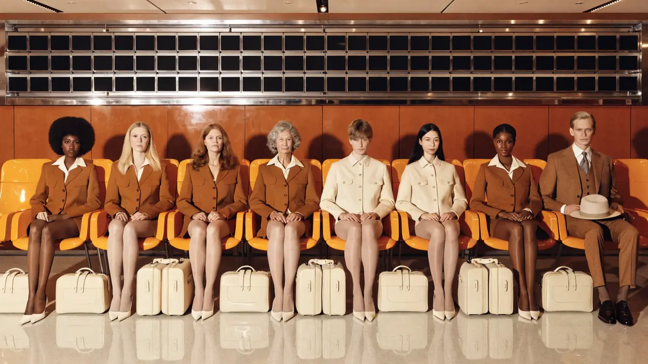 Eight people in matching tan uniforms seated in a row of orange seats