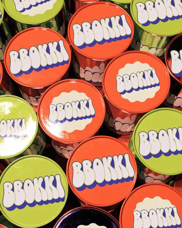 Glossy tangerine, lime and violet noodle cups packed edge to edge, each lid printed BBOKKI
